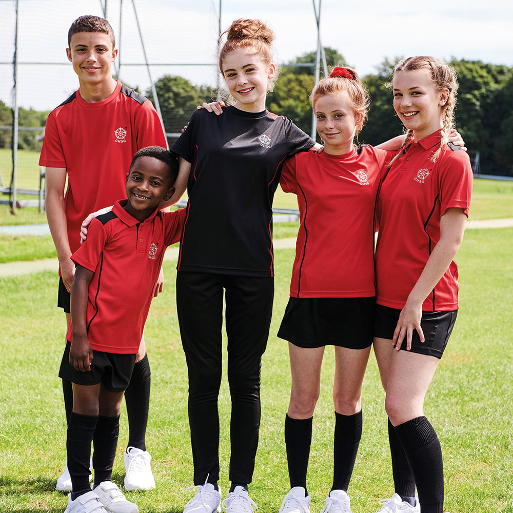 Children stood in a sports field wearing red and black Trutex sportswear kits 