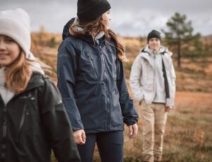 Three people stood outside wearing coats and hats by Isbjorn of Sweden
