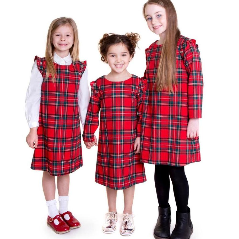 Three girls stood together wearing red tartan dresses by Lola Starr
