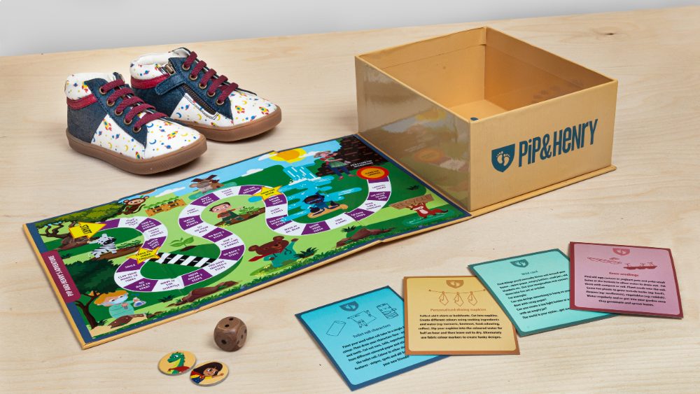 Pair of children's shoes beside a shoebox that doubles up as a boardgame 
