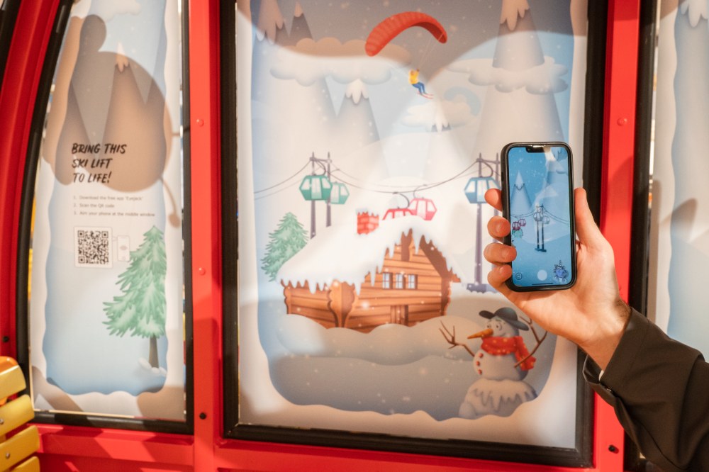 Someone holding up a mobile phone scanning a QR code on the Roarsome Express AR pop-up experience 