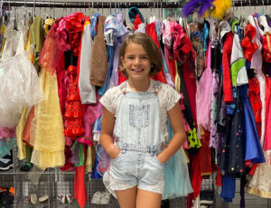 A young girl stood next to a rail full of clothes