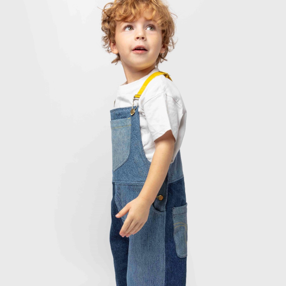 Boy stood against a white background wearing denim dungarees by Beyond Remade