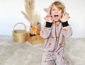 Child knelt on the floor wearing a fox print all-in-one