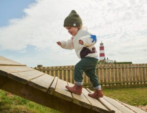 Young boy running up a wooden ramp outside wearing Start-Rite Shoes