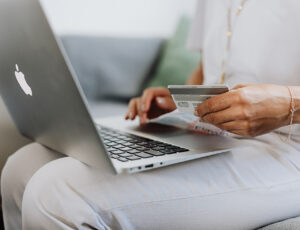 Woman holding a bank card while making a purchase on a laptop