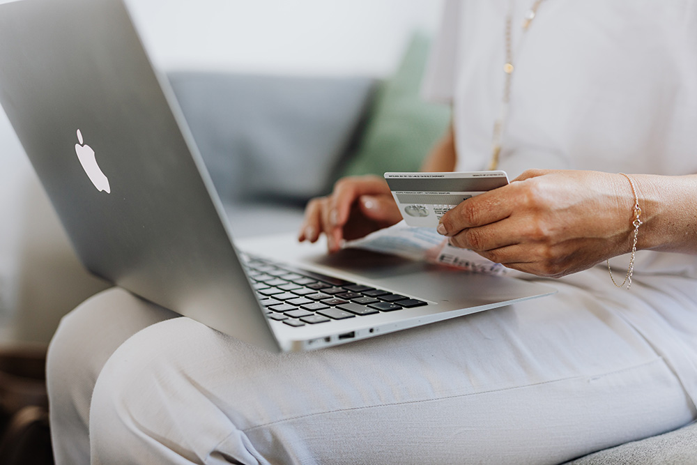Woman holding a bank card while making a purchase on a laptop