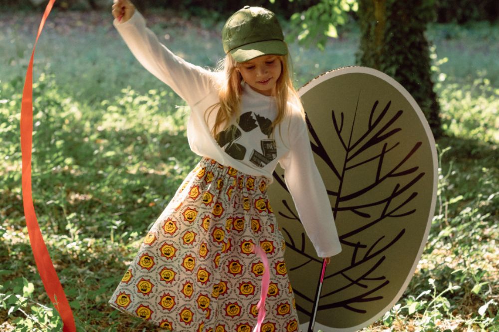 Young girl stood outside waving a ribbon and holding a large fan