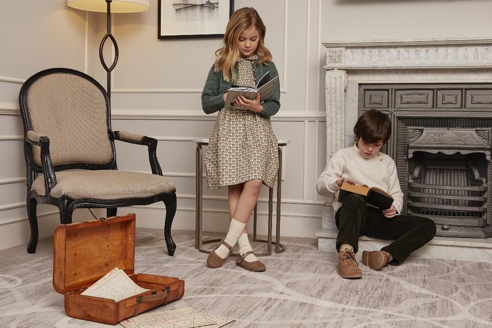 A girl and boy in a room reading books 