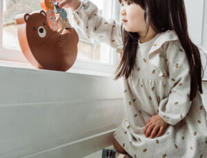 Girl playing with a wooden animal balancing game in window bottom