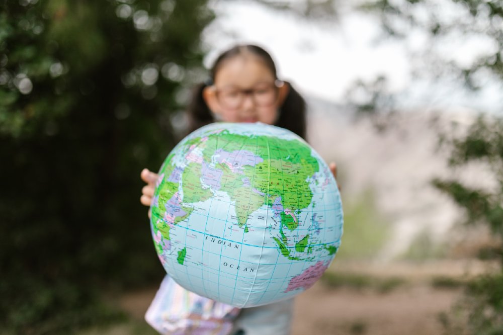 Young girl holding up an inflatable world globe