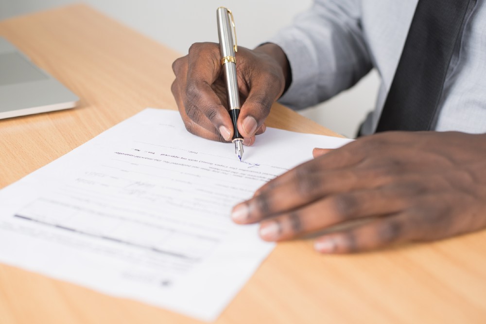 Close up of someone's hands as they sign business paperwork