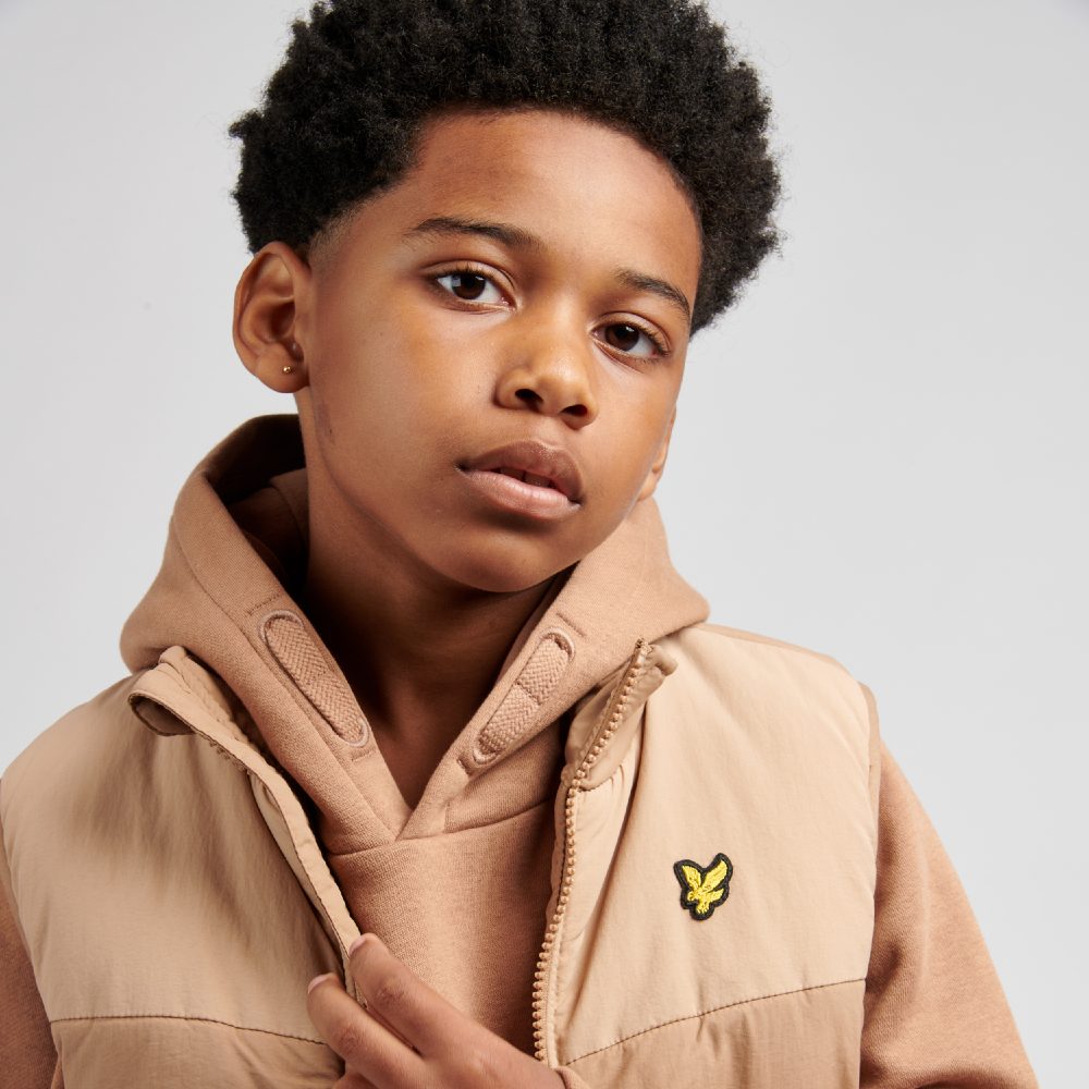 A young boy wearing a pink hoodie and jacket by Lyle & Scott