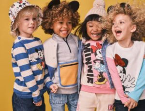 Four young children stood against a yellow background wearing the Disney collection by M&S Kids