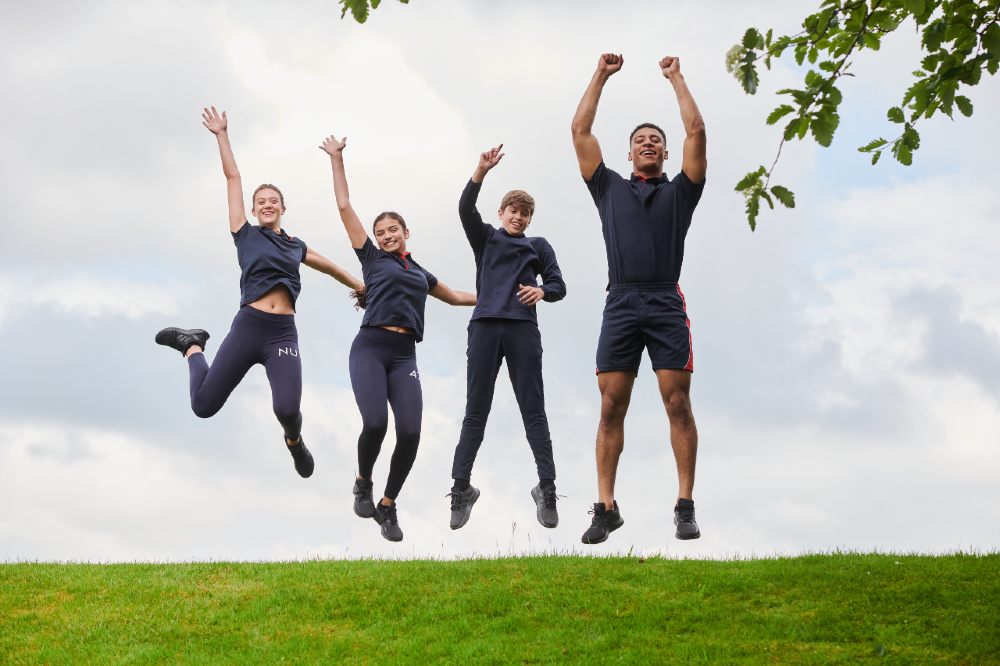 Four people outside jumping in the air wearing kits from Chadwick Teamwear
