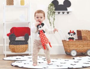 Young child stood in a room holding a Minnie Mouse doll by Rainbow Designs