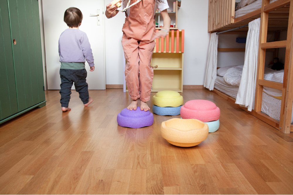 Two young children in a room playing with Stapelstein stepping stones