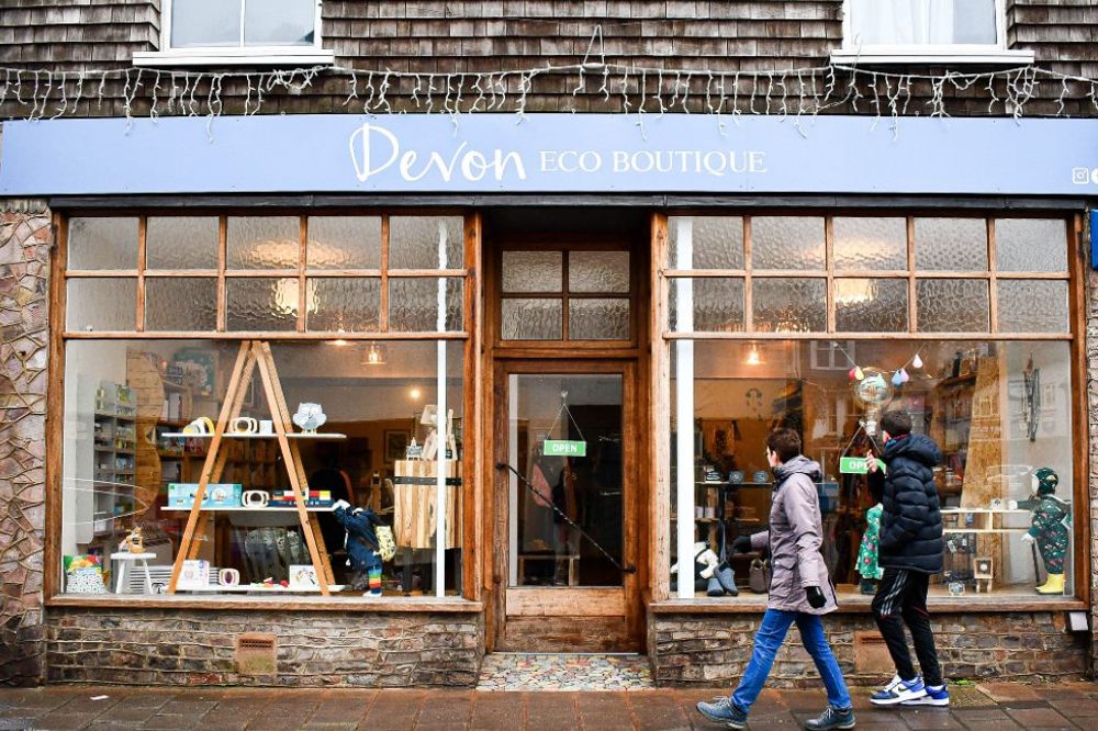 Two people walking past the store front of Devon Eco Boutique