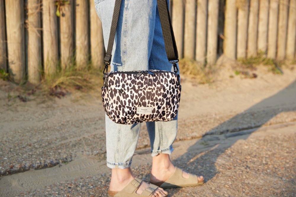 Woman stood outside with a leopard print Finnson changing bag on her shoulder