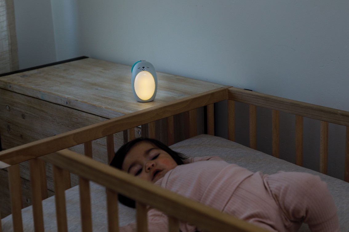 Baby sleeping in a cot beside a 3-in-1 Sounds & Lights Soothing Pal