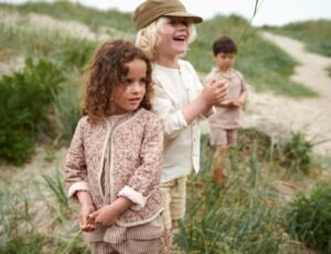 Children stood in grass outside wearing Wheat childrenswear
