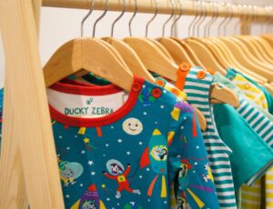 Brightly coloured children's clothes hung on a wooden rail on a stand at INDX Kids