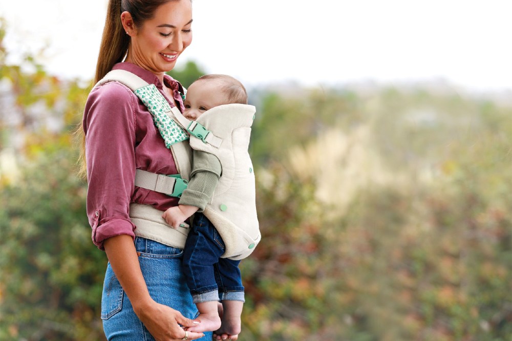 Women carrying a young child in the Infantino Flip 4-in-1 Nature & Nurture Convertible Carrier