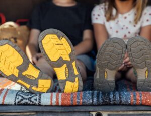 Two young children sat down with the soles of their Keen shoes visible