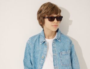 Young boy wearing a white T-shirt, blue shirt and sunglasses from the Messy Kids range