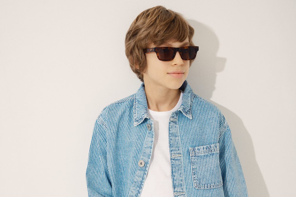 Young boy wearing a white T-shirt, blue shirt and sunglasses from the Messy Kids range