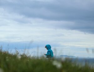 A child wearing a blue hoody walking outdoors