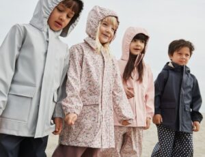Children stood in a row wearing rain coats and outerwear by Wheat