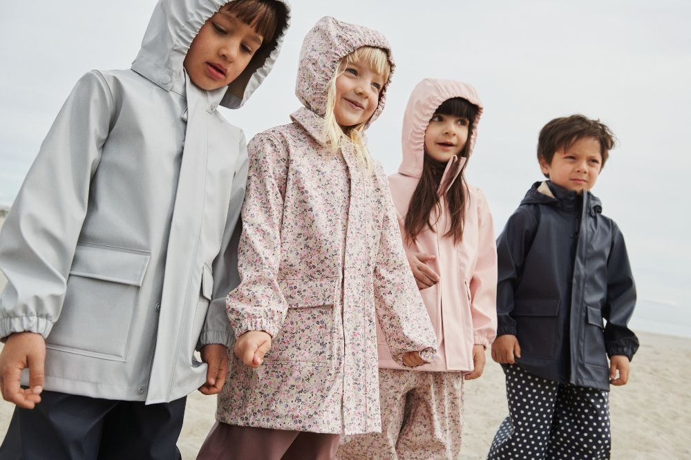 Children stood in a row wearing rain coats and outerwear by Wheat