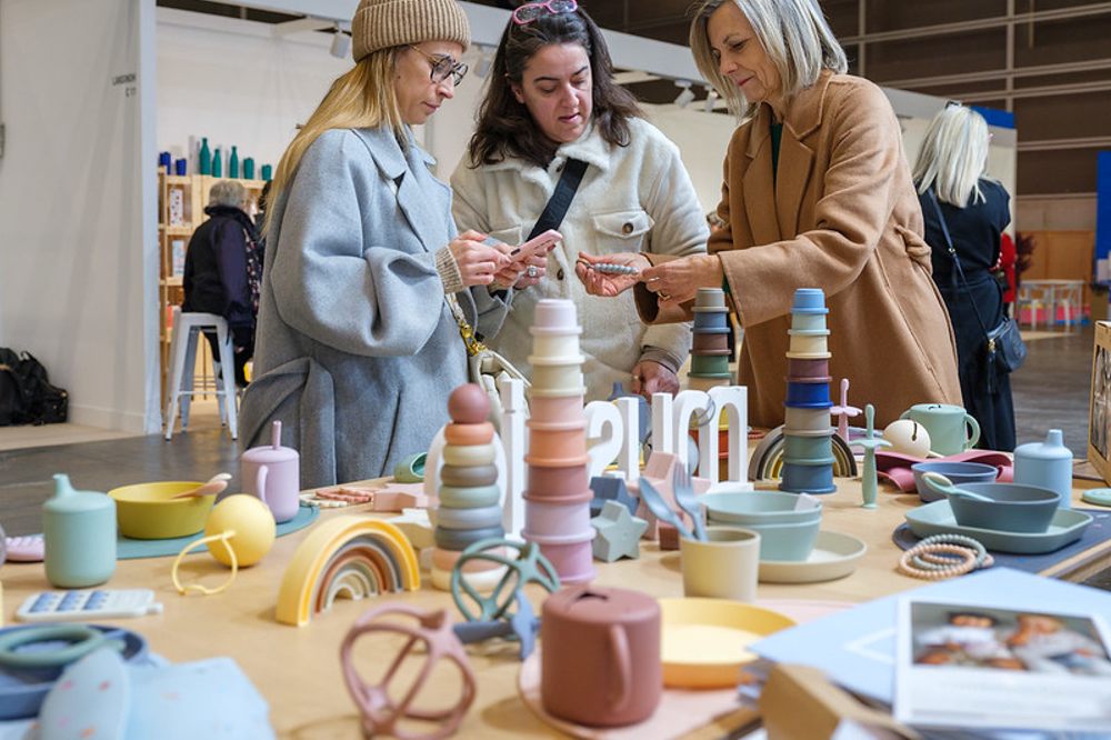 Women stood looking at a table of children's products at a trade show 