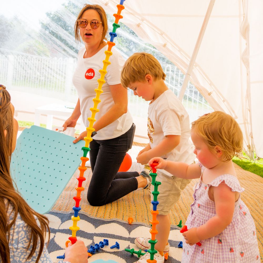 Adults and children inside a tent playing with children's toys 