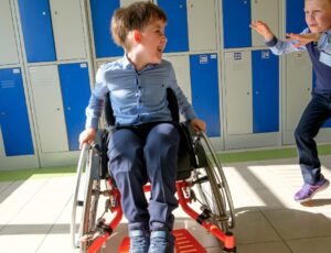 A young school boy in a wheelchair in front of school lockers