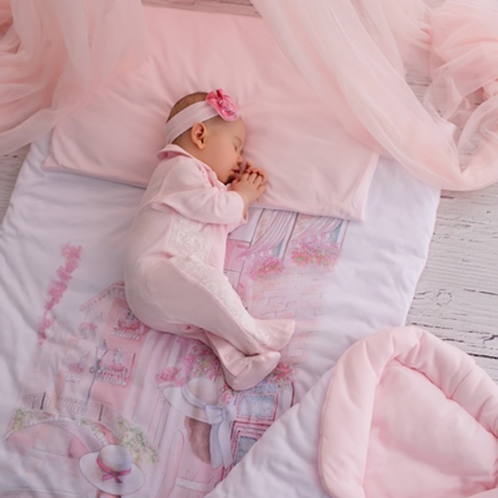 Young baby dressed in oink sleeping on pink bedding 