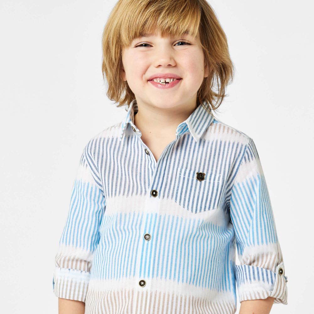 Young boy smiling at the camera wearing a striped shirt 