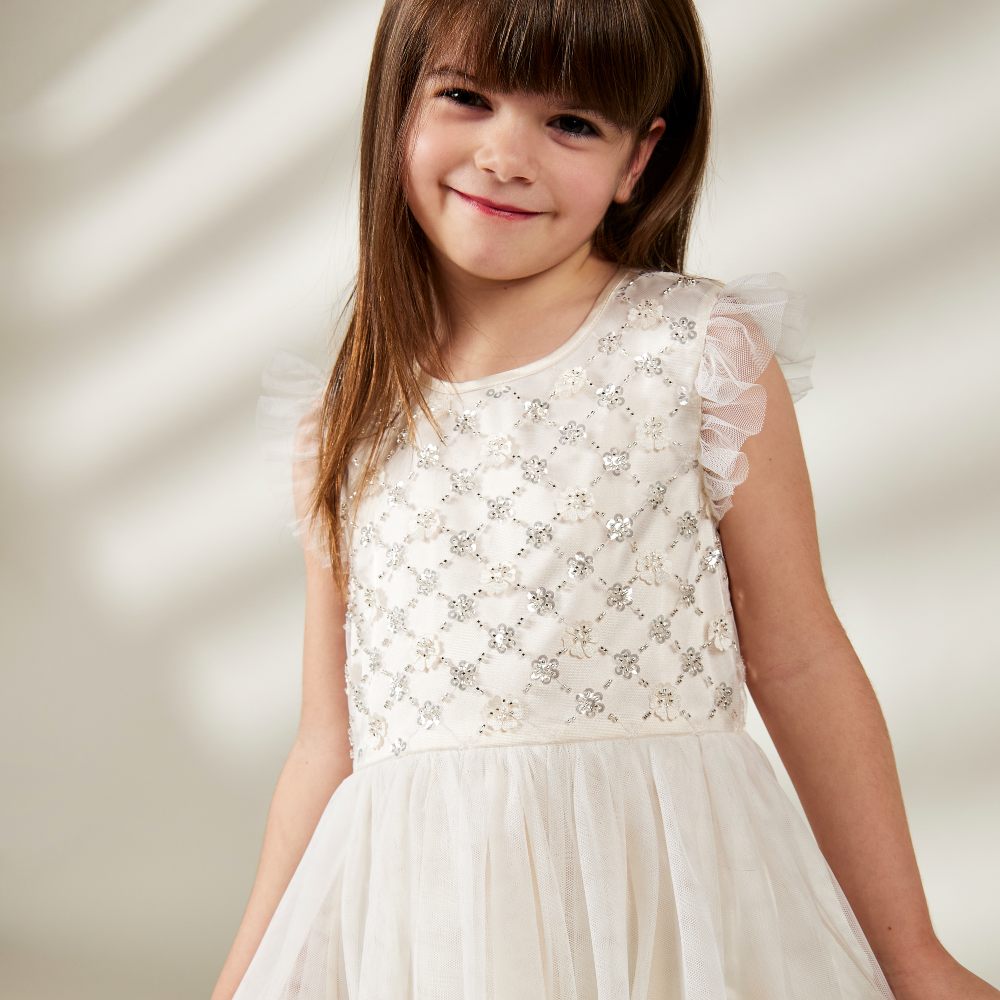 Young girl smiling wearing a white sparkly dress 