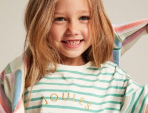 Young girl smiling wearing a striped T-shirt with Joules written on it