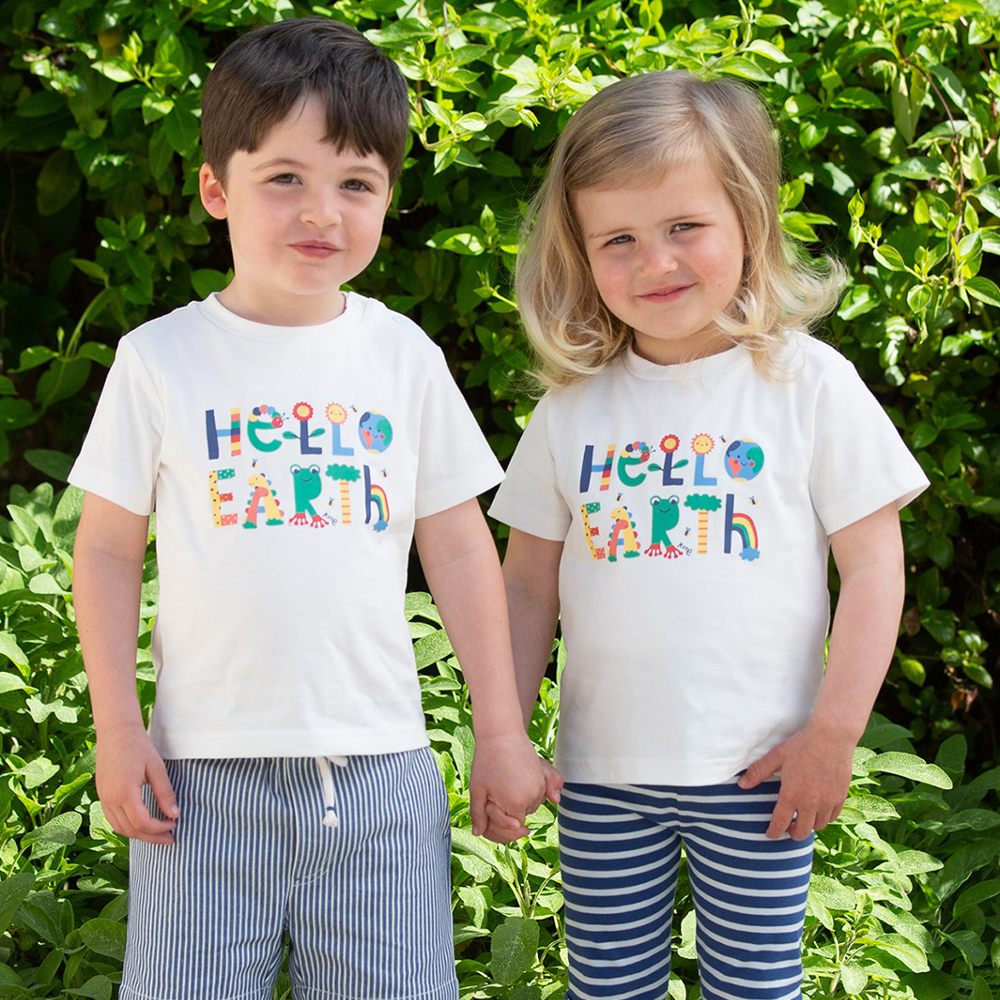 Two young children stood holding hands wearing T-shirts with Hello Earth written on them