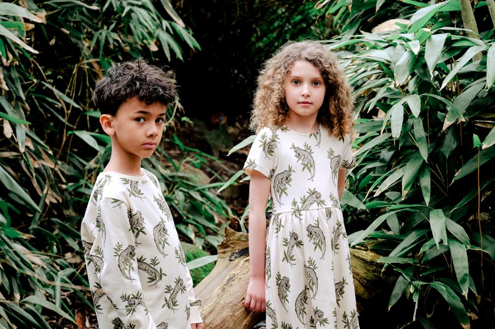 Two children stood in a wood wearing outfits with animal prints on them by MAI