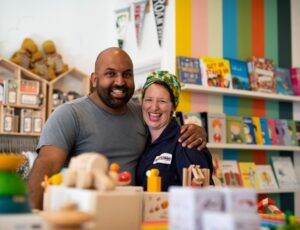 Couple stood with their arms around each other in a children's shop as part of Small Biz 100