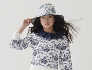 A girl in a blue and white print hat and top