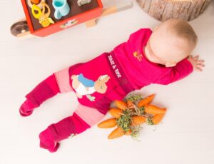 A baby lying on their front wearing a pink top and leggings with Peter Rabbit on which has been named as a finalist in The Licensing Awards