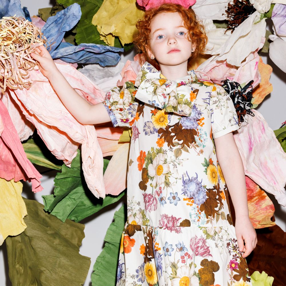 A young girl with red hair wearing a floral dress 