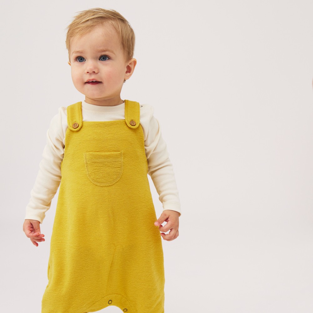 Young child wearing yellow dungarees 