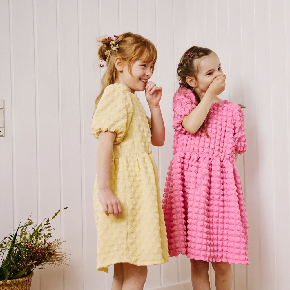 Two young girls wearing a yellow and pink dress 