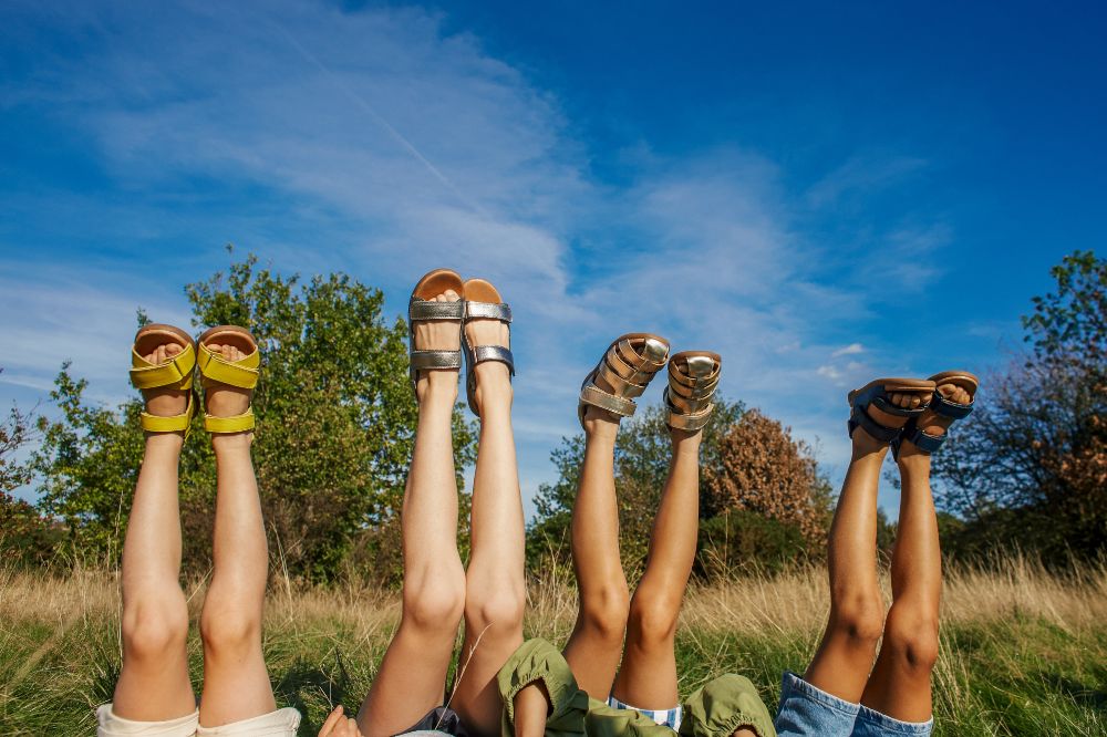 Four children lying in a field with their feet in the air wearing Zig + Star shoes