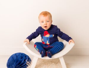 A baby sat in a white chair wearing a Paddington™ Bear top, leggings and socks by Blade & Rose